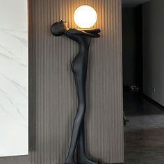 a statue is standing next to a wall with a lamp on it's side