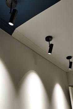 three spotlights are on the ceiling in an empty room