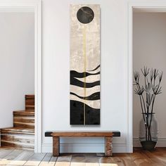 an abstract painting hangs on the wall next to a wooden bench in a white room