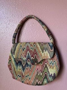 Carpet bag design handmade small purse with 11 inch round handle, flap over close and  pristine fully lined in cream color. No flaws to note. Good condition. Width 8 inches Length 7 inches.  $10 Vintage Evening Flap Bag, Vintage Multicolor Handheld Shoulder Bag, Vintage Shoulder Bag With Fold Over Clasp, Vintage Bag With Fold Over Clasp For Everyday Use, Vintage Bags With Detachable Handle, Vintage Multicolor Satchel With Handles, Vintage Bags With Rolled Handles, Vintage Multicolor Shoulder Bag With Top Carry Handle, Vintage Satchel With Rolled Handles For Daily Use