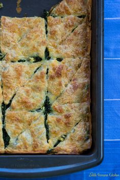 a casserole with spinach and cheese in a pan on a blue cloth