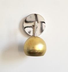 a round mirror mounted to the side of a wall next to a gold ball and metal object