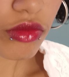 a close up of a woman with large hoop earrings on her nose and red lipstick