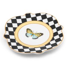 a black and white checkered plate with a butterfly on the center, in gold trim