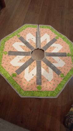 a quilted table topper sitting on the floor in front of someone's feet