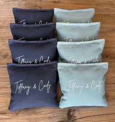 four personalized pillows on a wooden surface with the names of each pillow in white ink