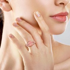 a woman wearing a pink ring with flowers on it's side and her hand next to her face