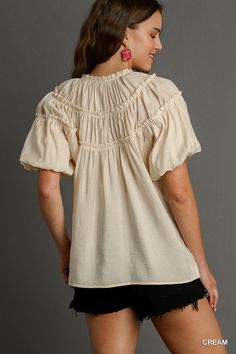 Experience effortless style and comfort with our Kate Modal Pleated Split Neck Ruffle Top in Cream! Made from soft modal fabric, this top features delicate pleating, a flattering split neck, and charming ruffle details. Elevate any outfit with this versatile and elegant top. Spring V-neck Puff Sleeve Top With Ruffles, Feminine Smocked Top With Gathered Neckline For Spring, Chic V-neck Smocked Top With Ruffles, Feminine Ruffled Puff Sleeve Peasant Top, Feminine Peasant Top With Puff Sleeves And Ruffles, Elegant Smocked Ruffle Top For Spring, Elegant Puff Sleeve Top With Ruffles, V-neck, Chic Blouse For Gatherings, Feminine Smocked Top With Ruffle Hem