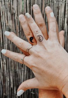 two hands with rings on their fingers and one has a small letter in the middle