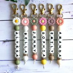 the key chains are decorated with flowers and letters that spell out what's in them