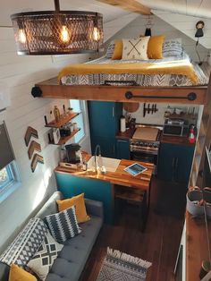 a loft bed sitting in the middle of a living room next to a kitchen and dining area