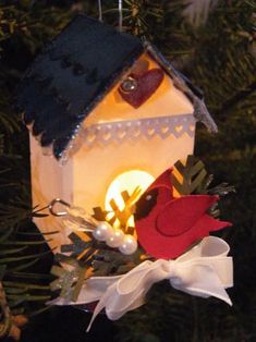 a birdhouse ornament hanging from a christmas tree with lights and decorations on it