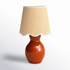 an orange table lamp with a beige shade on it's side and a white background