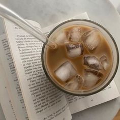 an iced drink in a glass with ice cubes and a book on the side