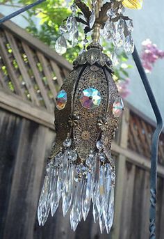 a lamp hanging from a metal pole with flowers on it's top and bottom