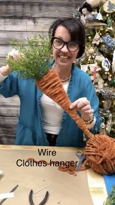 a woman is holding up a piece of yarn with scissors in front of a christmas tree