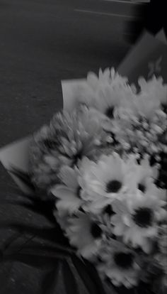 black and white photograph of flowers on the ground in front of a person holding an umbrella