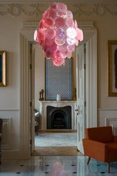 a chandelier hanging from the ceiling in a living room next to a fire place