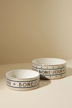 two white bowls sitting on top of a table with black and white designs around them