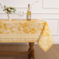 a table topped with a bottle of wine next to a vase filled with white flowers