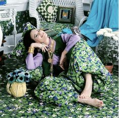 a woman sitting on the floor in green and white pajamas with her hand under her chin