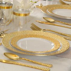 the table is set with gold and white plates, silverware, and napkins