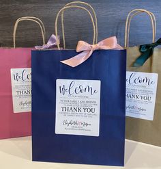 three blue shopping bags with pink bows and thank you tags on them are sitting next to each other