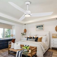 a bed room with a neatly made bed and a ceiling fan in the middle of it