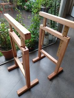 two wooden benches sitting next to each other in front of a planter filled with potted plants