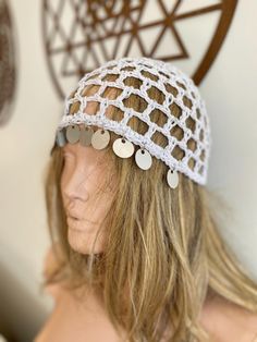 a mannequin head wearing a white crochet hat with metal discs on it