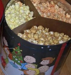 two tins filled with popcorn sitting on top of a wooden table