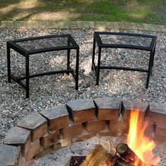 an outdoor fire pit with two chairs sitting on it's sides next to the fire