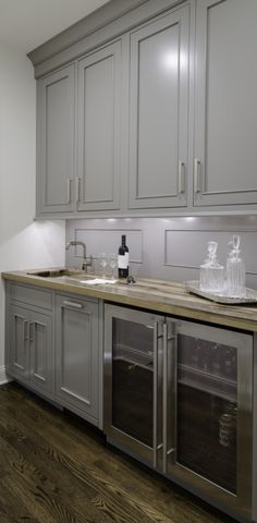 a kitchen with gray cabinets and wooden counter tops on top of a hard wood floor