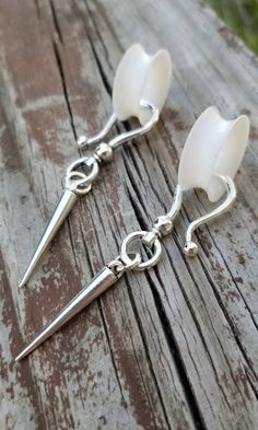 pair of white glass and silver plated earrings on wooden table with grass in the background