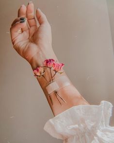 a woman's arm with pink flowers on it and two sticks sticking out of the wrist