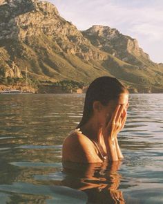 a woman sitting in the water with her hands to her face