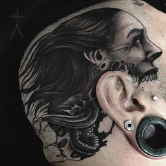 a man's head with a tattoo on it and an ear piercing in the shape of a skull