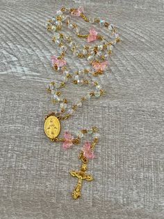 Handcrafted Catholic prayer rosary. Traditional 5 decade chain style rosary. It is made with a delicate gold plated crucifix and matching gold plated Virgin Mary medallion.  Translucent pink butterfly beads and clear faceted iridescent crystal 6mm glass beads.  Each bead is hand placed, turned and connected.  This butterfly garden rosary is beautiful and light weight. Makes a perfect gift.  The rosary is handmade in Florida.  Made with love.  Many Blessings. ♥️ Gold Crucifix Rosary For Jewelry Making, Handmade Gold Rosary For Healing, Gold Spiritual Rosary For First Communion, Gold Rosary With 8mm Beads For Healing, Handmade Gold Healing Rosary, Gold Beaded Crucifix Rosary, Gold Spiritual Rosary Bracelet For Healing, Matching Promise Rings, Butterfly Beads