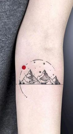 a tattoo on the arm of a person with mountains in the background and a red dot