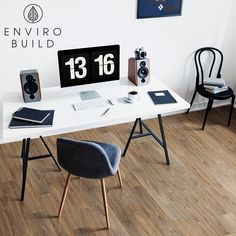 a desk with a computer and speakers on top of it in front of a white wall