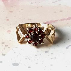 You are looking at a stunning, vintage, pre-loved, 9 ct. Solid Yellow Gold Garnet Cluster Ring set with a larger central round garnet with a halo of 8 smaller stones. The central cluster is supported on large, open arrowhead shaped shoulders with bark decoration to the leading edges. An unusually designed ring with gorgeous blood red garnets.  The ring is stamped on the inner shank with a full set of UK Hallmarks detailing the makers mark, "9 "& "375" confirming the gold purity of 9 ct., the Ass Cluster Ring Set, J Us, Dream Engagement, Dream Engagement Rings, Ring Stand, Blood Red, Multi Stone Ring, Red Garnet, Multi Stone