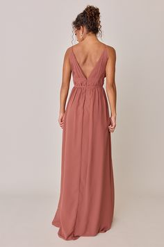 the back of a woman wearing a long, dusty pink dress with spaghetti straps and an open v - neckline