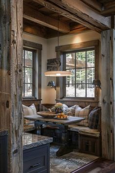 a living room filled with furniture next to two windows and a wooden table surrounded by pillows