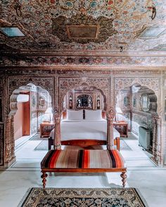 an ornately decorated room with a bed and rugs on the floor in front of it