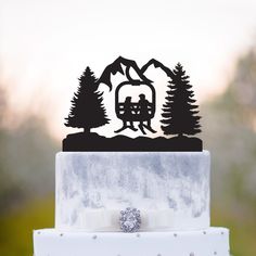 a wedding cake topper with a couple on a ski lift in the mountains and trees