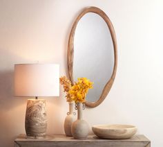 a table with a lamp, vase and mirror on it