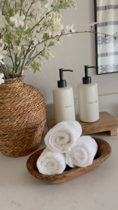 towels and soaps are sitting on a tray in front of a vase with flowers