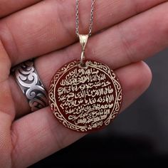 This 14k gold plated silver ayatul kursi necklace is a beautiful and meaningful piece of jewelry that combines the power of the holy verse with the energy of the red agate stone. The Ayatul Kursi is the 255th verse of the 2nd surah of the Quran and is considered one of the most powerful verses in Islam. The verse is hand-written in elegant calligraphy on a red agate stone, set in a silver pendant. The red agate is believed to promote strength and courage, making this necklace not only beautiful but also imbued with powerful energy. The necklace hangs from a matching silver chain and is perfect for daily wear. It's a great way to keep the blessings and protection of the Ayatul Kursi close to your heart. Are you looking for a truly unique and special piece of jewelry? Look no further than ha Carved Yellow Gold Necklace Perfect For Gift, Carved Yellow Gold Necklace For Gift, Carved Yellow Gold Necklace, Red Engraved Amulet Necklace, Traditional Gold Agate Necklace, Gold Amulet Style Agate Necklaces, Gold Agate Amulet Necklace, Gold Agate Amulet Necklaces, Etched Pendant Necklace For Blessing