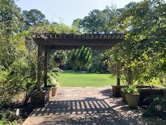 an open walkway in the middle of a park with lots of trees and plants on either side