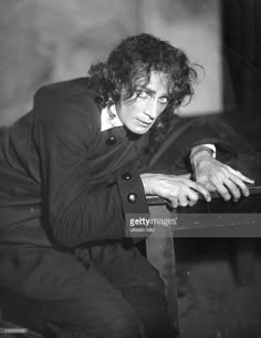 an old black and white photo of a man with curly hair sitting at a table